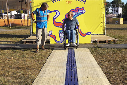 Une personne en fauteuil roulant manuel teste le CAU-mobility installé sur l’herbe