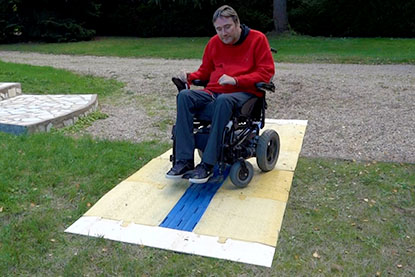 Une personne en fauteuil électrique roule sur le CAU-mobility